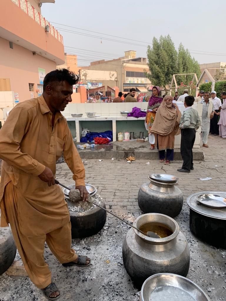 A cook stirs large pots of food for patients and families