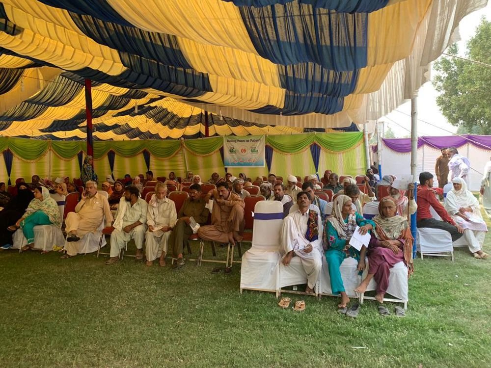 Hundreds of patients seated beneath a striped marquee, waiting to be seen at the Just4Aid eye camp in Sahiwal, 2019