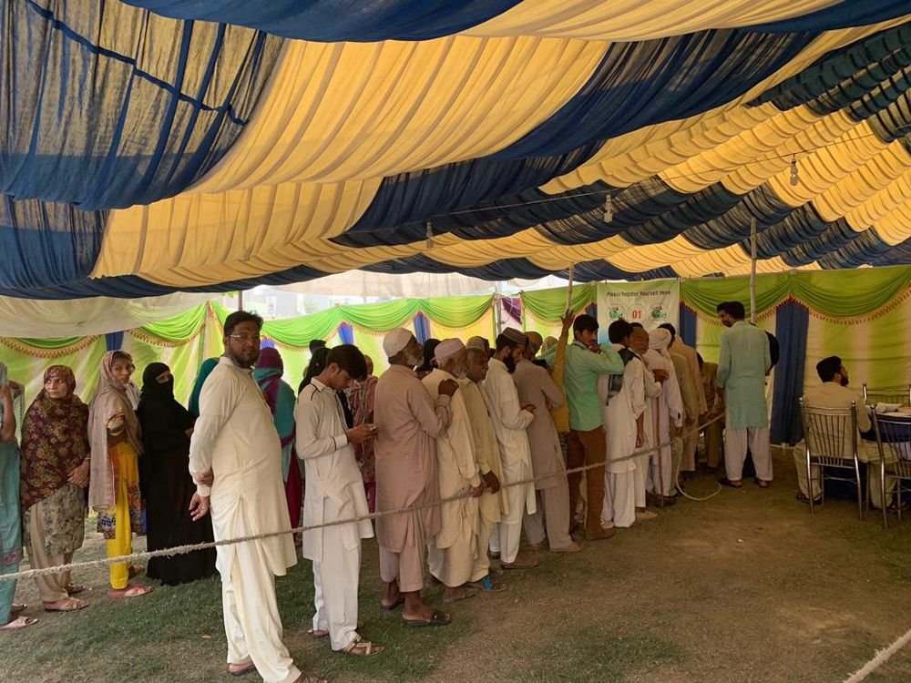 Patients queue under a blue and yellow marquee to register at the 2019 Sahiwal eye camp