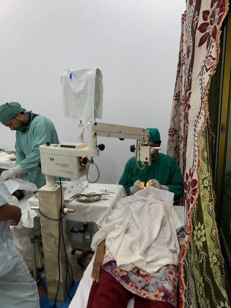 A surgeon operates on a patient at the operating microscope