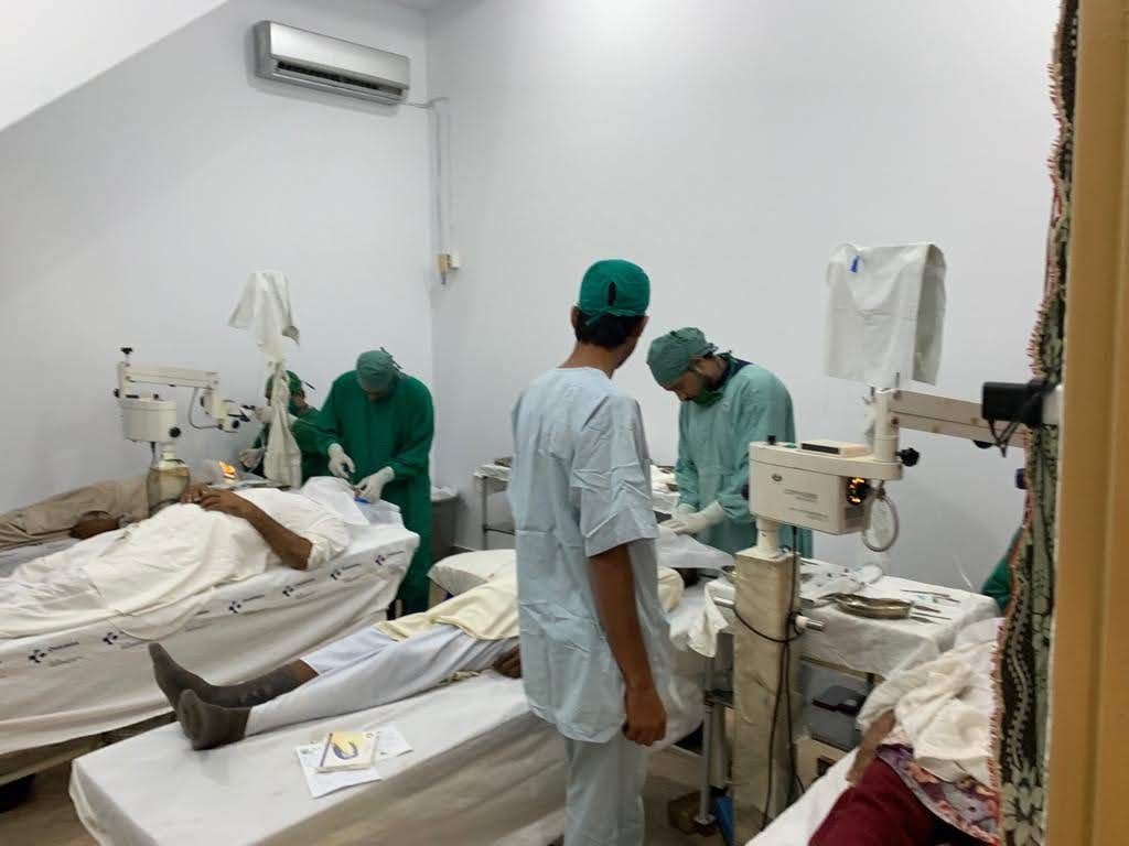 Patients lying on beds in the theatre with surgical staff nearby