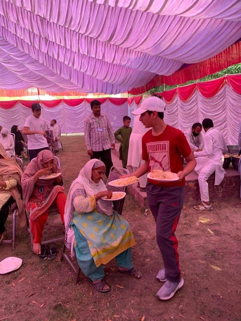 A volunteer hands a plate of food to a woman in the waiting area at the 2019 camp