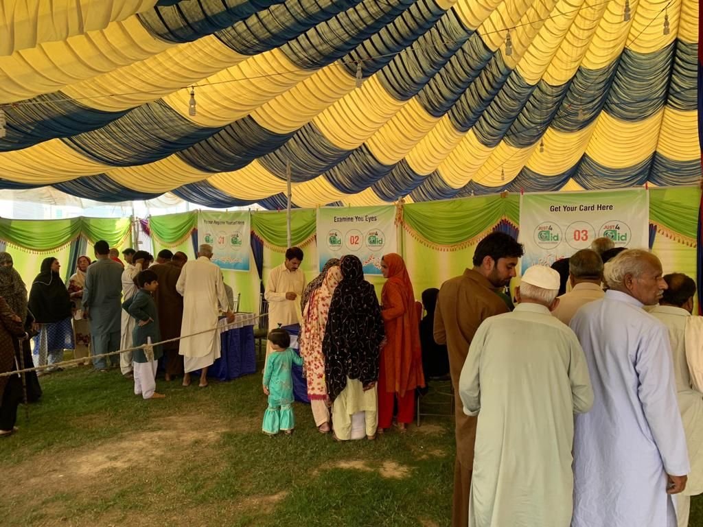 A crowd of patients waiting under the blue and yellow marquee