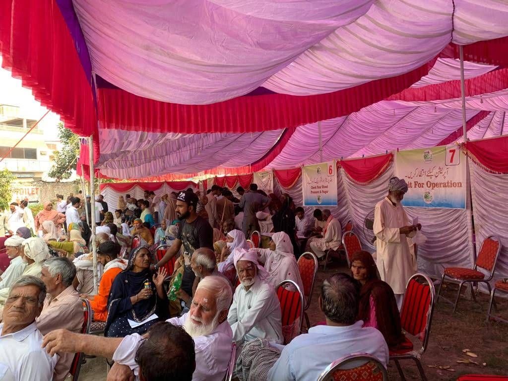Patients seated in rows in the waiting marquee