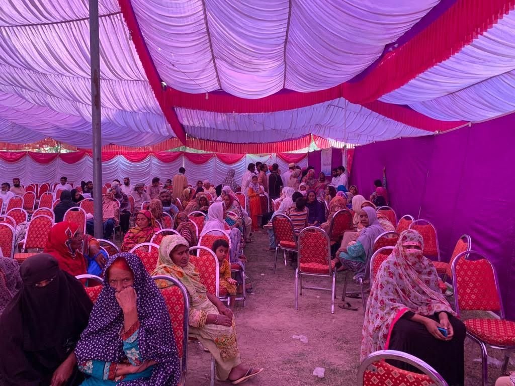 A crowded waiting marquee with red chairs